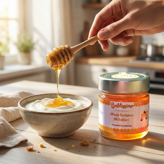 Miele millefiori artigianale Baldissimo colato da dosamiele in legno su yogurt bianco, con vasetto sul tavolo.